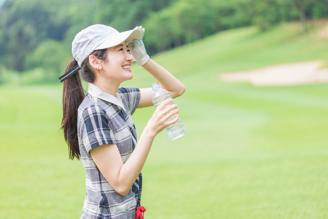 ゴルフ場で水を飲むゴルファーの女性